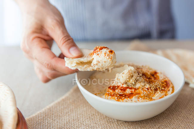 Mãos mergulhando pão pita no húmus — Fotografia de Stock