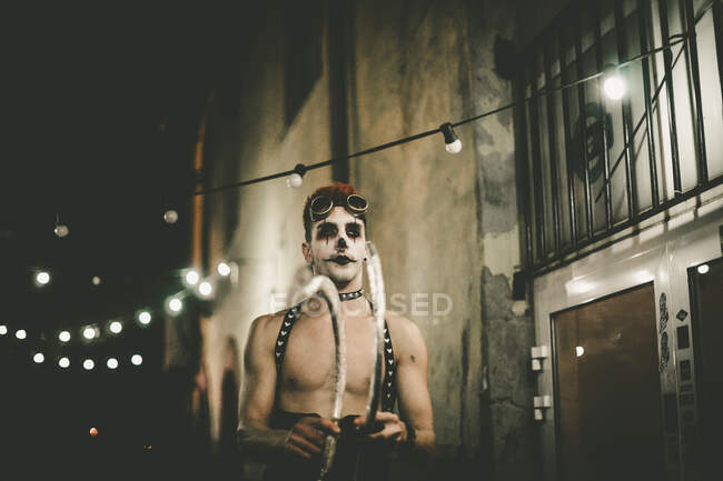 Человек с нарисованным лицом и очками ходит без топора на маскарад Хэллоуина по ночам. — стоковое фото