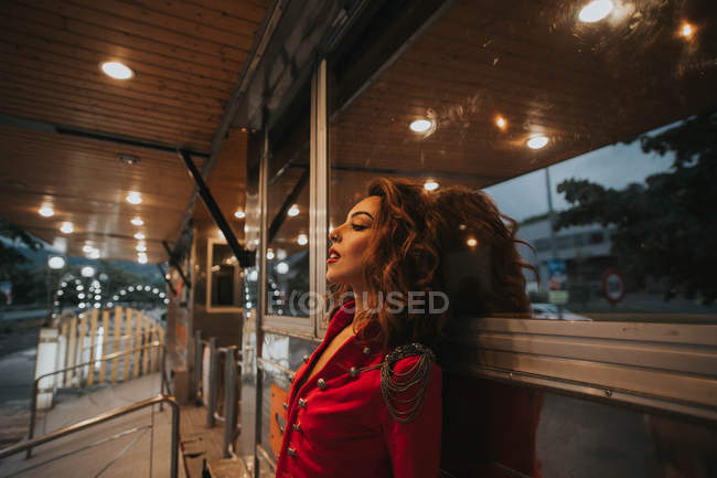 Брюнетка жінка в червоне пальто, спираючись на стіні — стокове фото