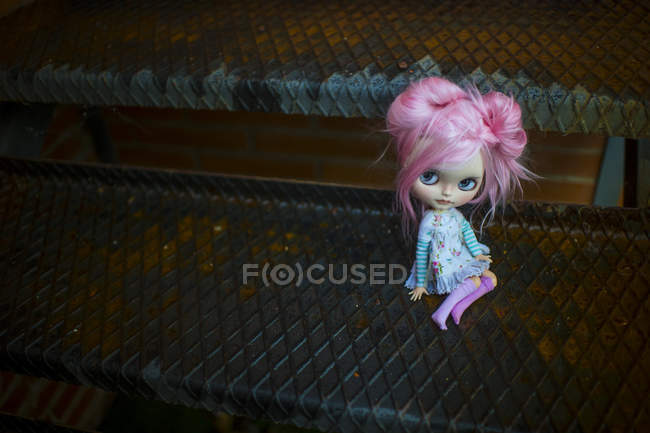 Vue rapprochée de poupée moderne aux cheveux roses assise sur des escaliers en métal — Photo de stock