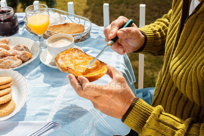 Cropped image of man making toast at table — Stock Photo
