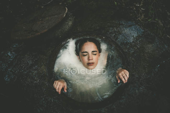 Woman delved in well with poured milk — Stock Photo