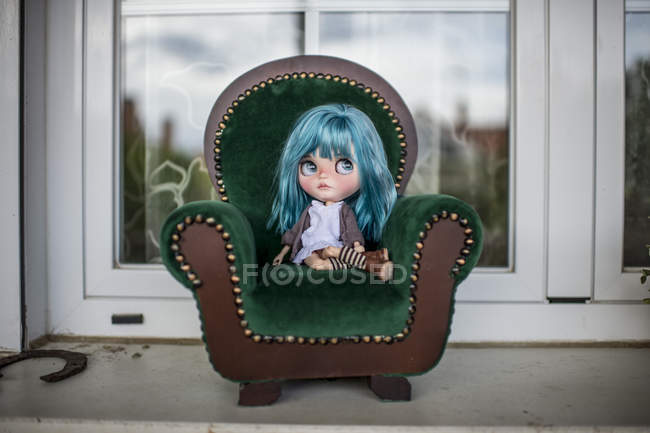 Vista de perto da boneca moderna de cabelos azuis sentada em uma poltrona pequena — Fotografia de Stock