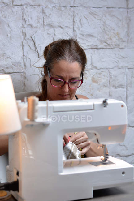 Женщина портной в очках вышивки на рабочем месте — стоковое фото