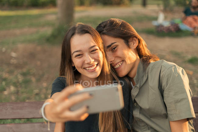 Портрет молодой улыбающейся пары, делающей селфи со смартфоном . — стоковое фото