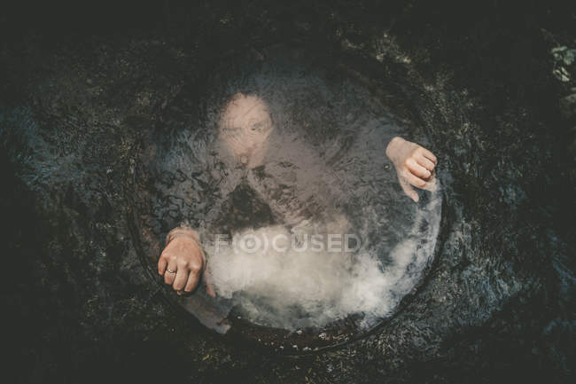 Girl underwater in well holding edges — Stock Photo