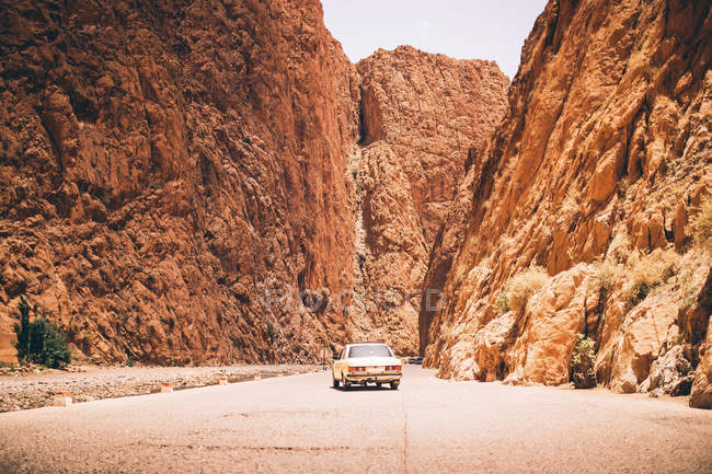 Покинутий жовтий автомобіль стоїть в каньйоні між двома піщаними горами — стокове фото