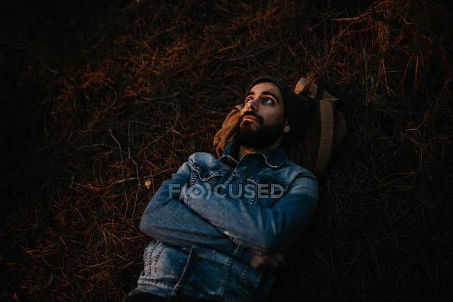 Bärtiger Mann liegt im Herbstwald auf dem Boden. — Stockfoto