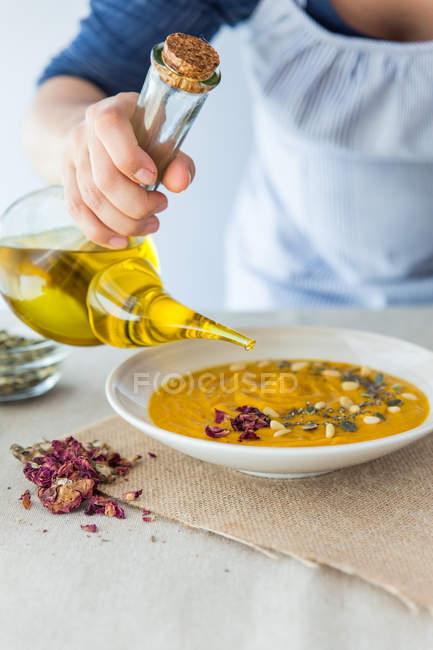 Cook pouring oil in cream soup — Stock Photo