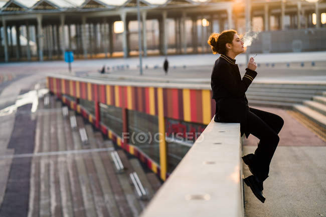 Mulher sentada e corrimão e fumar cigarro — Fotografia de Stock