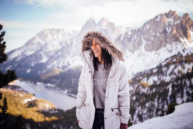 Cheerful brunette girl in white coat at mountain scene — Stock Photo