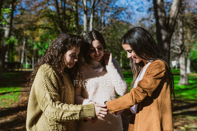 Retrato de três jovens mulheres conversando e sorrindo lá fora no parque — Fotografia de Stock