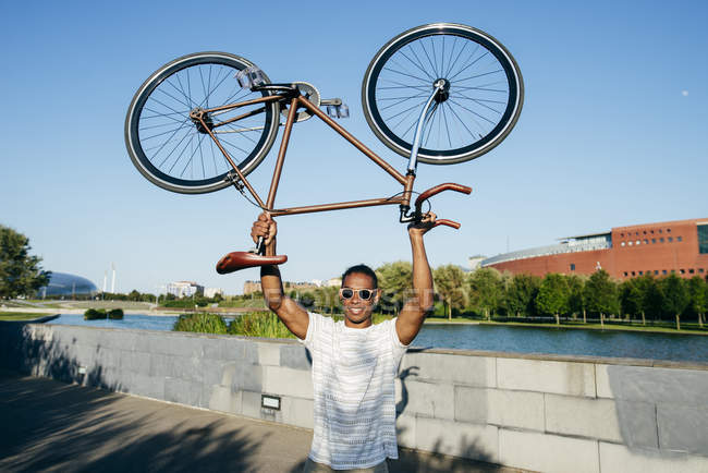 Hombre sosteniendo bicicleta por encima - foto de stock