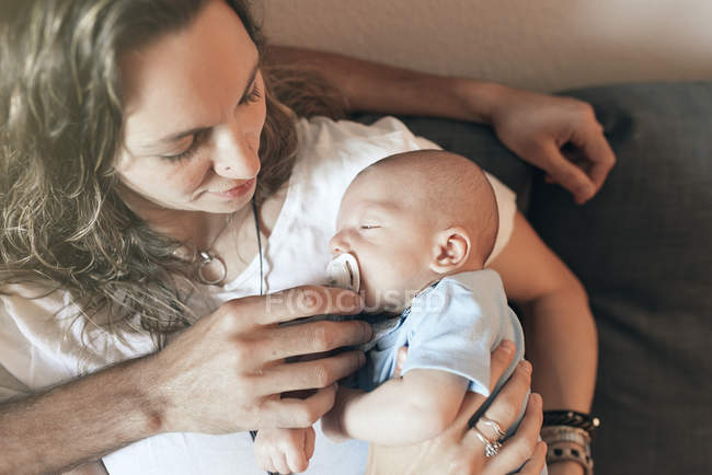 Мама сидит на тренере и держит новорожденного ребенка под рукой — стоковое фото