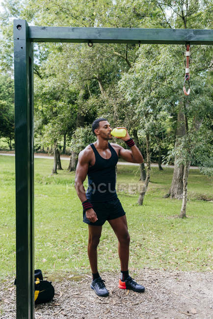 Muscular man drinking near bar — Stock Photo