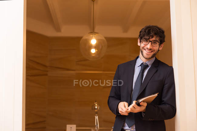 Homme positif en costume formel tenant un cahier et regardant la caméra . — Photo de stock