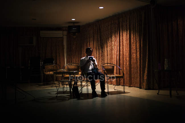 Малайзія-12 травня 2016: Людина в костюмі, сидячи на стільці в сутінки зал та проведення диска в коробці. — стокове фото