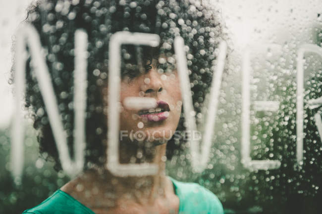 Menina morena posando atrás de vidro com letras nunca palavra — Fotografia de Stock