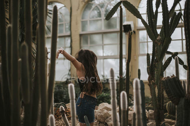 Menina morena posando com os braços estendidos no jardim botânico — Fotografia de Stock