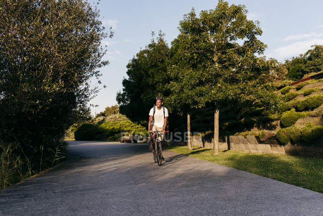 Чоловік їде на велосипеді на парковій алеї — стокове фото