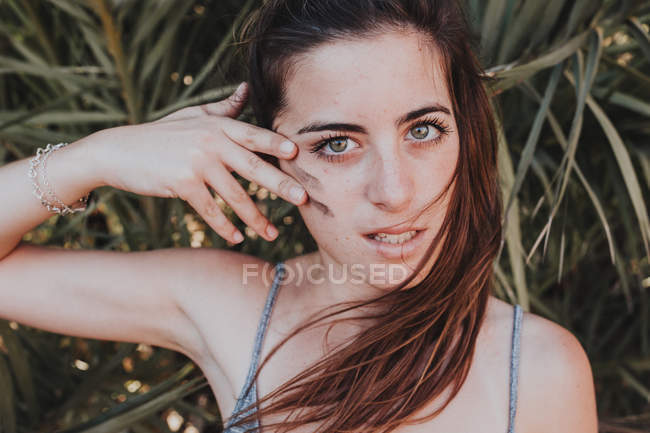 Ritratto di giovane bruna che dipinge camuffamento sulla guancia e guarda la macchina fotografica — Foto stock