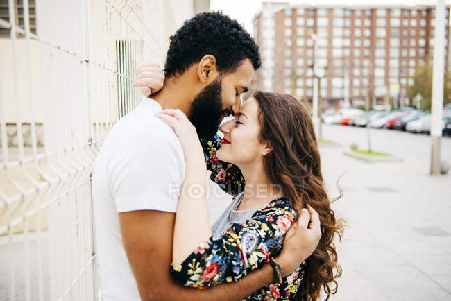 Pareja feliz abrazando y besando en la calle - foto de stock