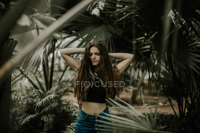 Brunette girl posing with hands behind head at botanical garden — Stock Photo