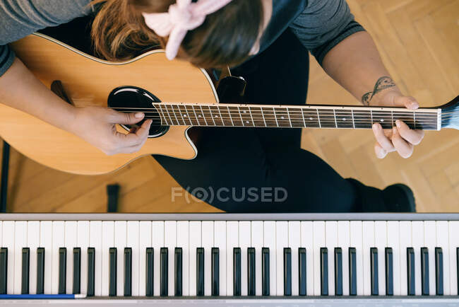 Молода жінка звукозапис гітари і фортепіано в його домашній звуковій студії . — стокове фото