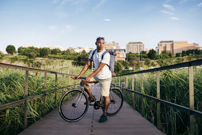 Человек позирует с велосипедом на набережной — стоковое фото