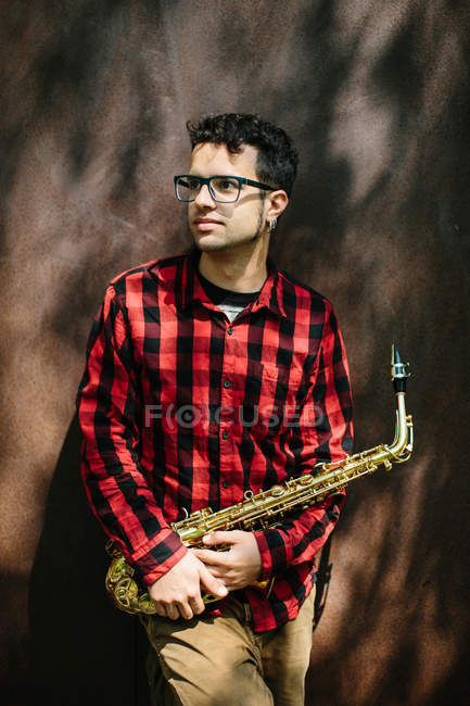 Музикант в окулярах стоїть з саксофоном — стокове фото