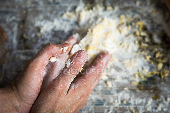 Над видом рук, отбивающих тесто для лимонного торта на деревенском деревянном столе — стоковое фото