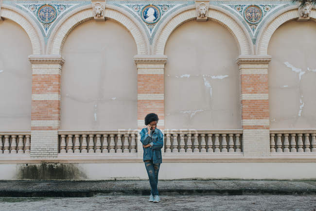 Fernsicht des Mädchens in Jeanskleidung beim Telefonieren in der Nähe der grauen Wand — Stockfoto