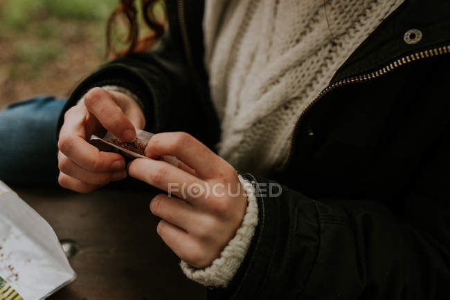 Обрезание женских рук катание сигареты — стоковое фото