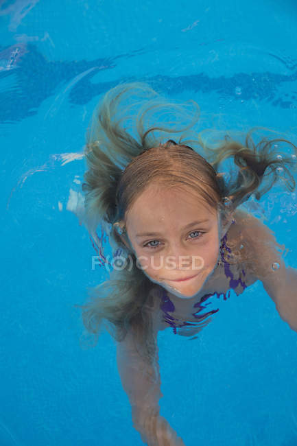 Enfant nageant dans la piscine et regardant la caméra — Photo de stock