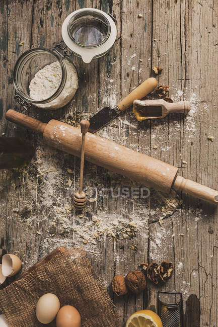 Vue du dessus des ingrédients de boulangerie et rouleau à pâtisserie sur table en bois rustique — Photo de stock