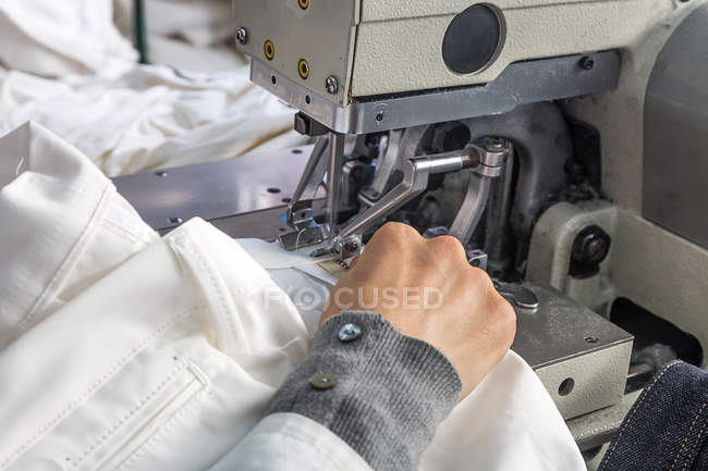 Mãos de colheita costurando em máquinas na fábrica — Fotografia de Stock
