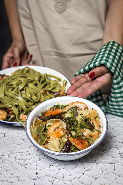 Crop female hands showing plates of italian green tagliatelle with seafood — Stock Photo