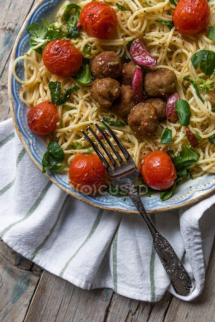 Spaghettis et boulettes de viande garnis de feuilles de basilic et de tomates grillées sur un plateau — Photo de stock