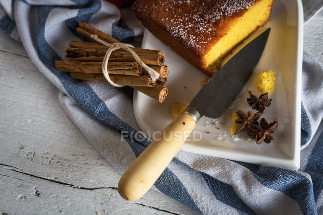 Crop image of plate with homemade cake, knife and spices on towel — Stock Photo