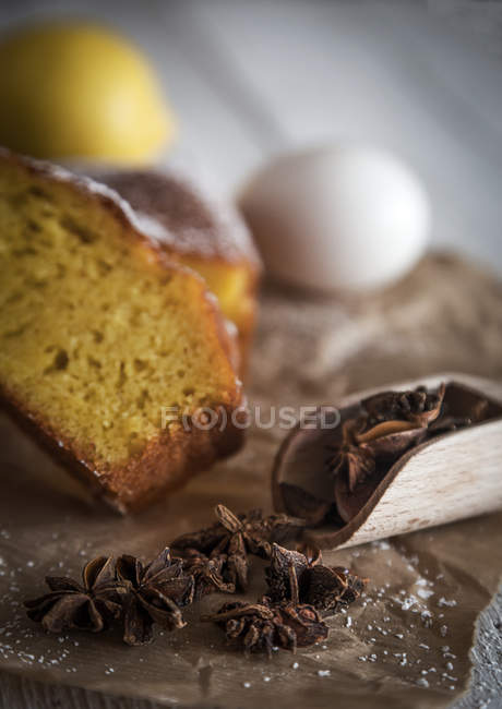 Close up view of scoop with anise stars on bakery paper over homemade cake slices and egg — Stock Photo