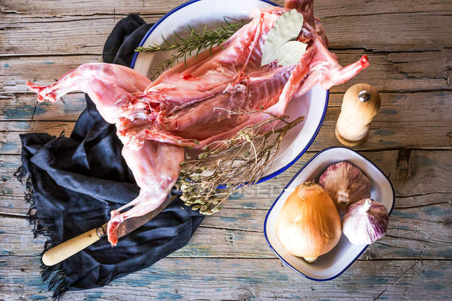Carcassa di coniglio crudo con ingredienti su tavola di legno — Foto stock