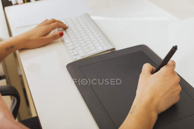 Mains féminines utilisant le clavier et la tablette graphique — Photo de stock