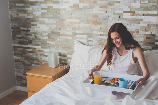 Garota segurando bandeja com café da manhã na cama — Fotografia de Stock