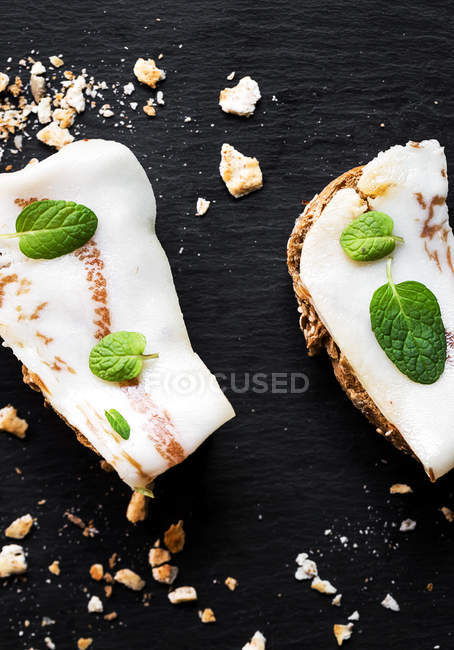 Бутерброды с солоноватым беконом и мятными листьями на доске — стоковое фото