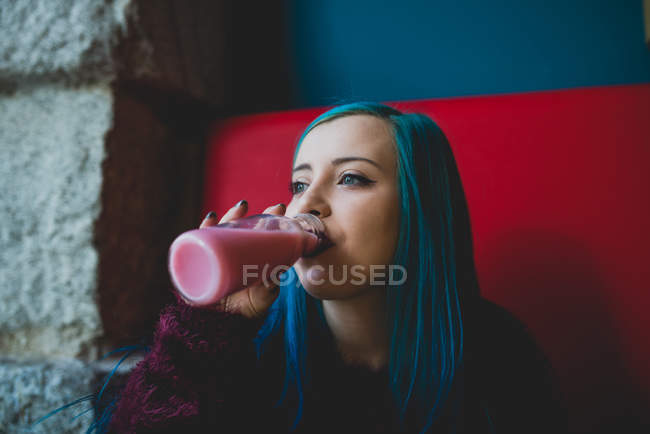 Портрет девушки с голубыми волосами, пьющей йогурт в кафе — стоковое фото
