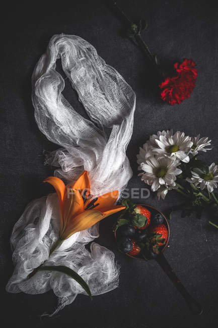 Mistura criativa de morangos com mirtilos e flores com tecido de olhar na velha mesa de madeira — Fotografia de Stock