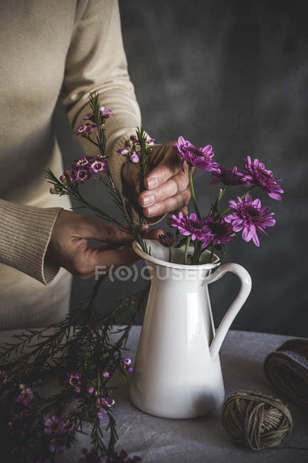 Pflanzenbild einer Floristin, die Blume in Keramikvase auf den Tisch stellt — Stockfoto