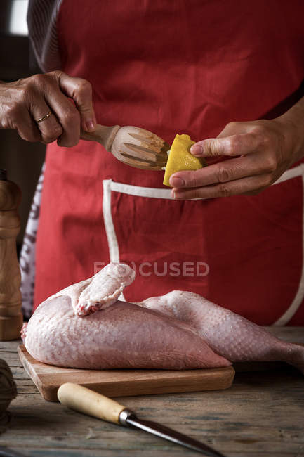Nahaufnahme einer Frau, die frische Zitrone auf rohes Huhn drückt — Stockfoto