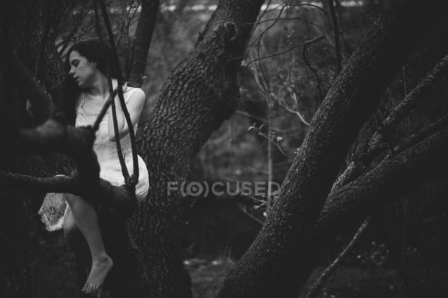 Dramatic girl posing on tree branch — Stock Photo