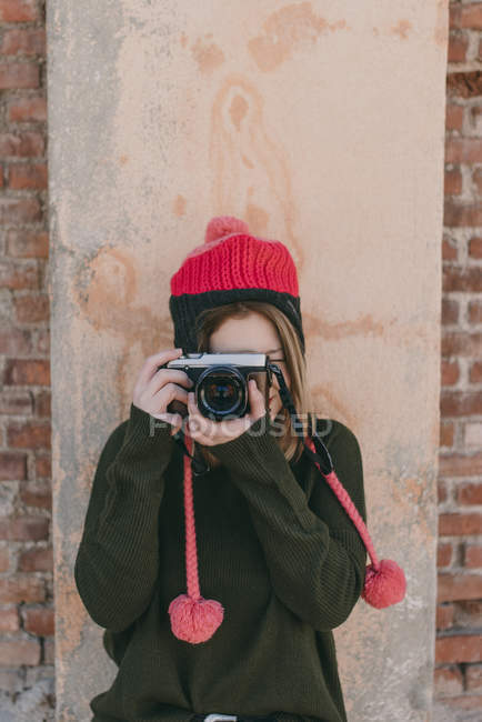 Fille en bonnet tricoté prenant des photos — Photo de stock
